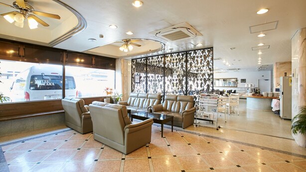 A hotel lobby with seating areas, a reception desk, and a view of the street.