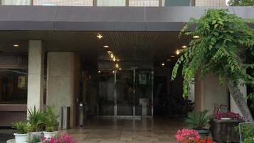 A hotel entrance with a covered walkway, potted plants, and a glass door leading inside.