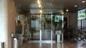 A modern building entrance with a tiled floor, glass doors, and a ceiling with linear patterns.