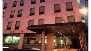 A multi-story hotel with a modern design, featuring a prominent entrance with a covered area and a glass facade.