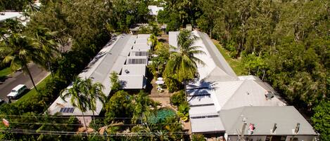 An aerial view of a resort with multiple buildings, surrounded by lush greenery and palm trees.