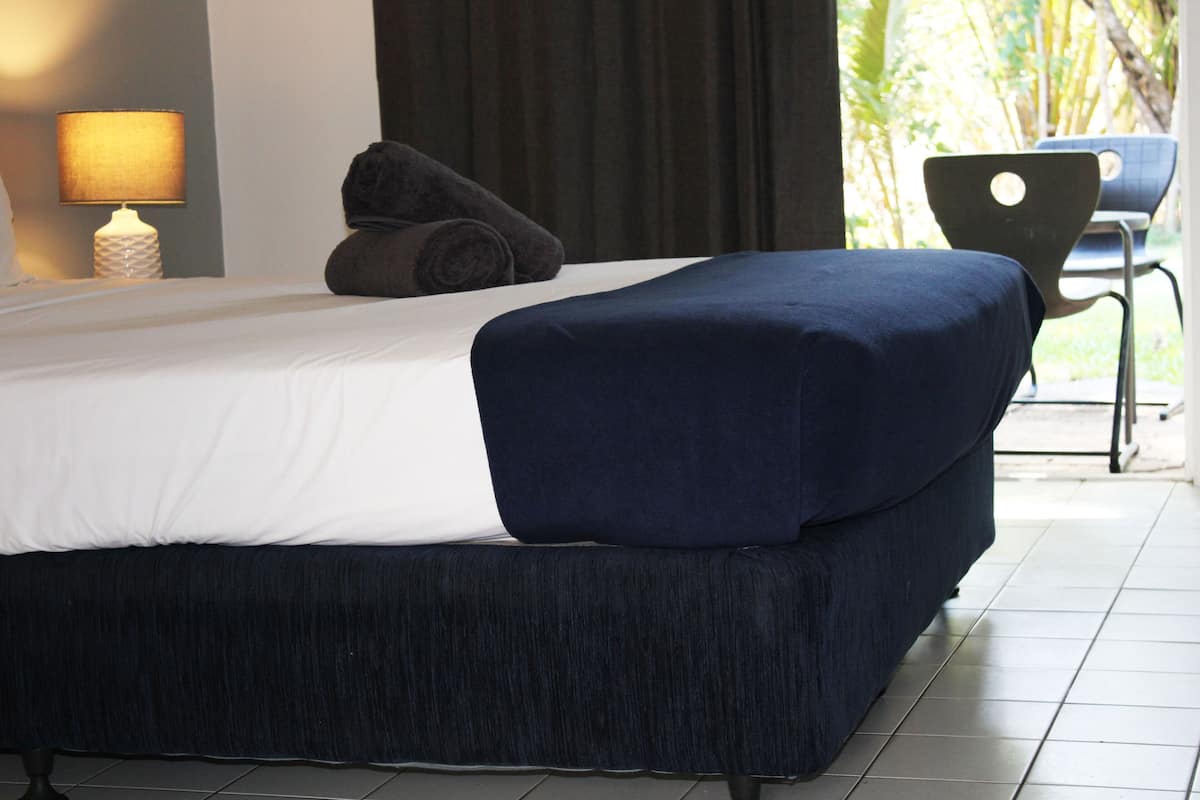 Quarto moderno com uma cama grande, abajur e vista para o exterior.