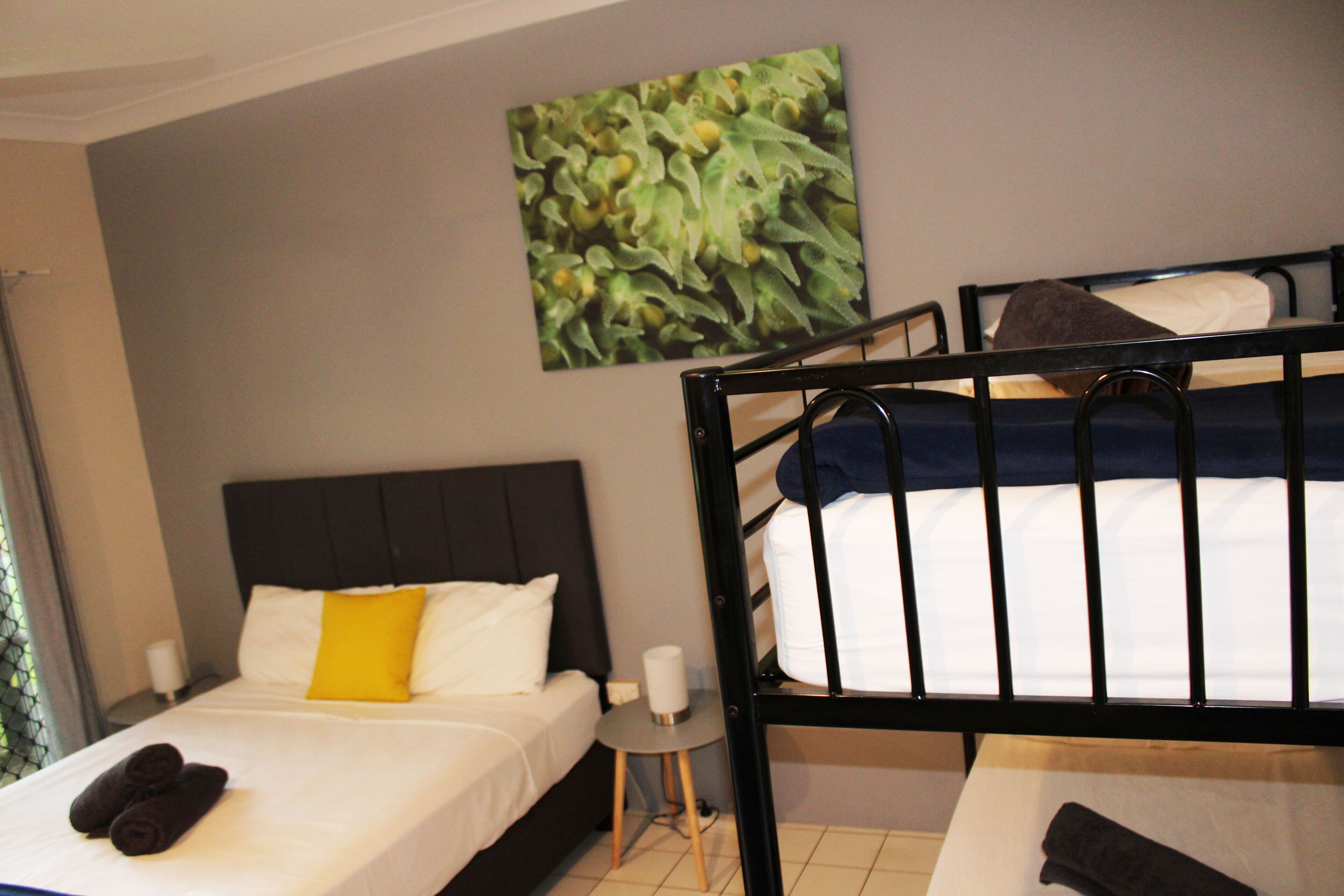 Una habitación de hotel con cama, una mesita y una obra de arte colgada en la pared.
