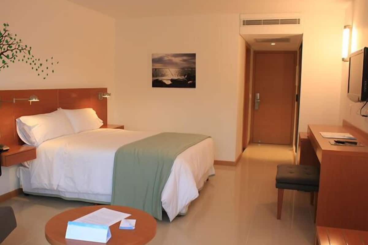 Une chambre d’hôtel comprenant un lit, un bureau, une chaise, une petite table et un téléviseur.