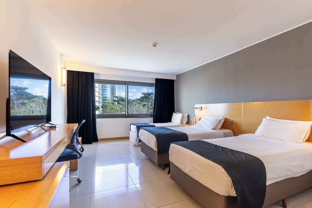 Une chambre d’hôtel avec deux lits, un bureau et une télévision.