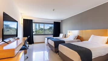 A hotel room with two beds, a desk, and a TV.