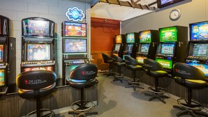 A row of slot machines with a neon sign above them and a clock on the wall. - Ocean Beach Hotel (Dunedin)