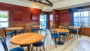 A restaurant interior with wooden tables and blue chairs, red walls, and a sign for Speight's. - Ocean Beach Hotel (Dunedin)
