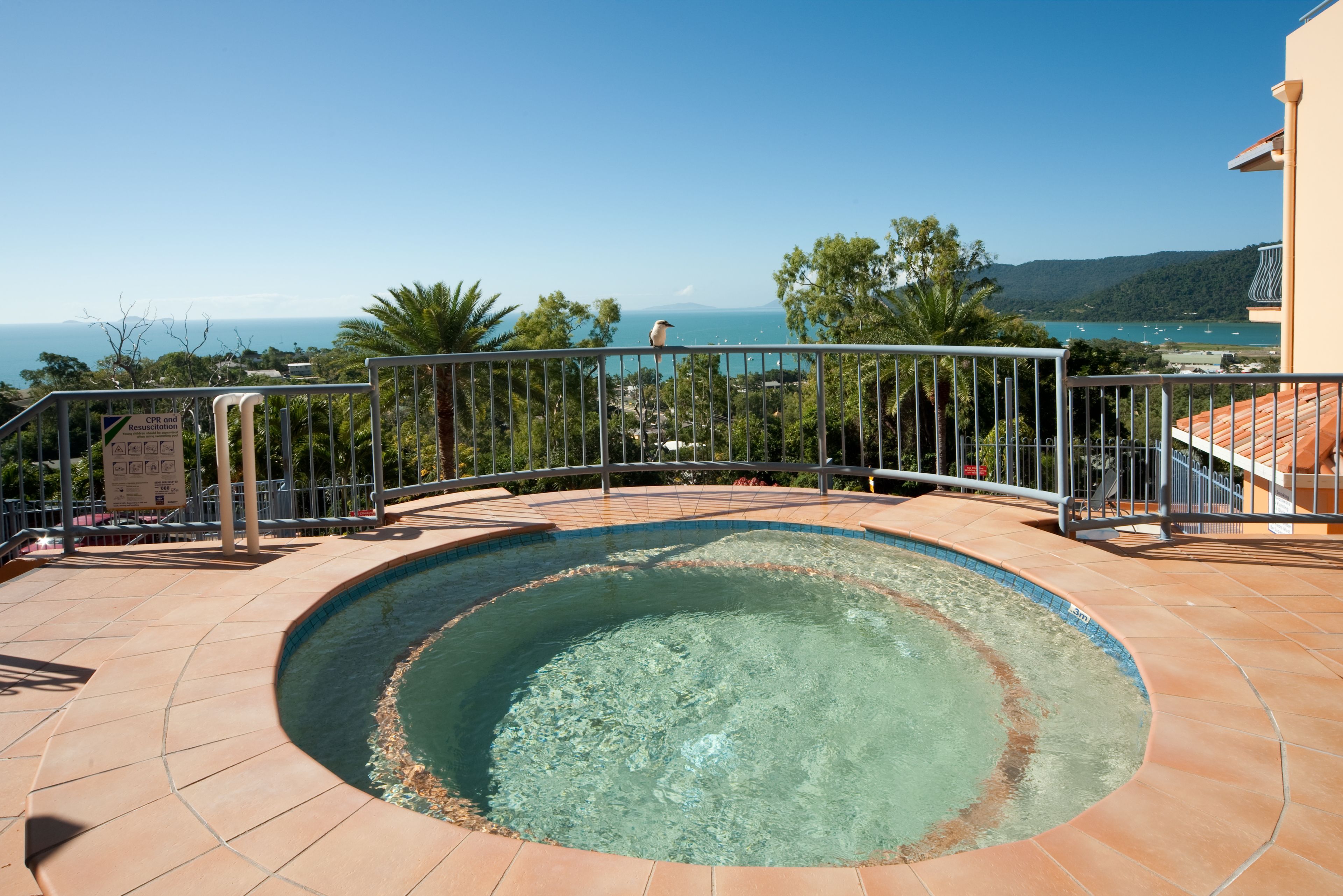Una piscina circular con vista despejada al mar y a las montañas al fondo.