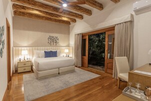 A bedroom with a large bed, bedside tables, a desk, and a view of the outdoors through a sliding glass door.