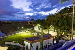 A well-lit outdoor area with a pool, seating, and a view of the surrounding landscape.