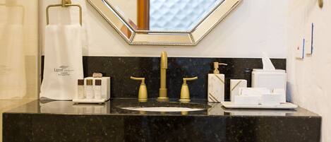 A bathroom with a black marble sink, gold faucets, and a mirror with a decorative frame.