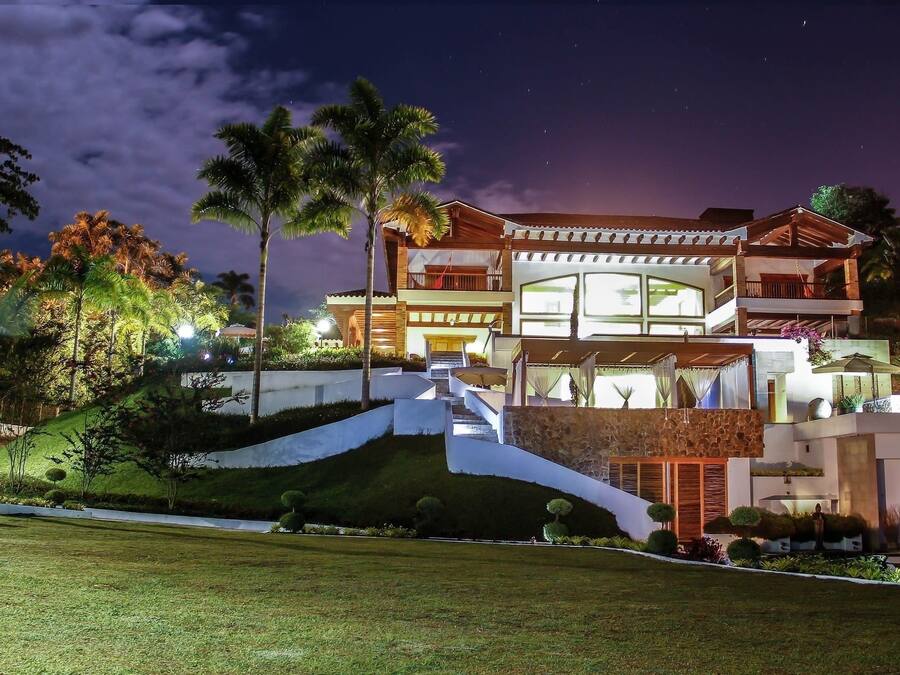 A multi-story house with a prominent staircase, large windows, and a well-maintained garden.