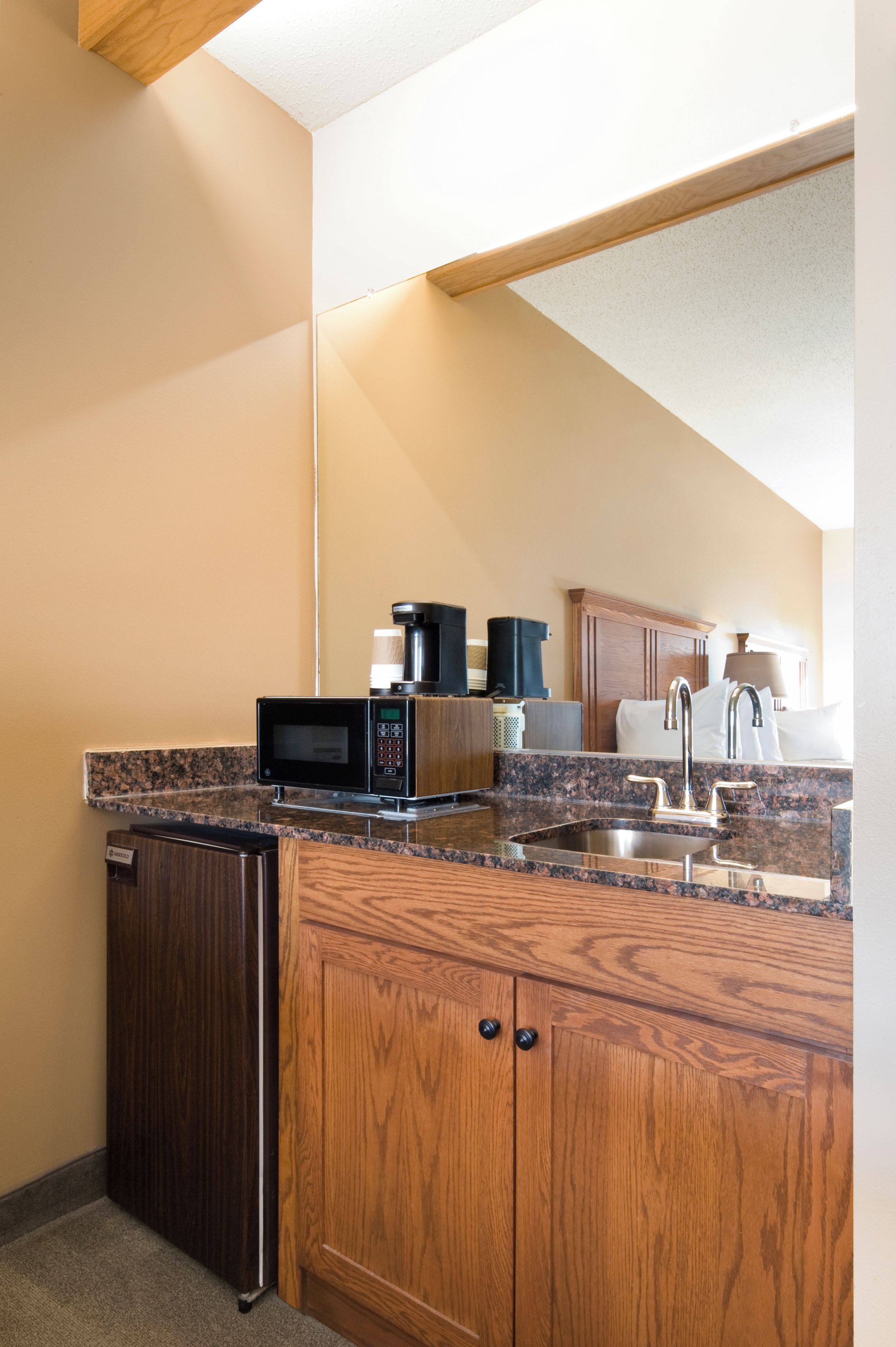 A compact kitchen with a microwave, coffee maker, and sink.