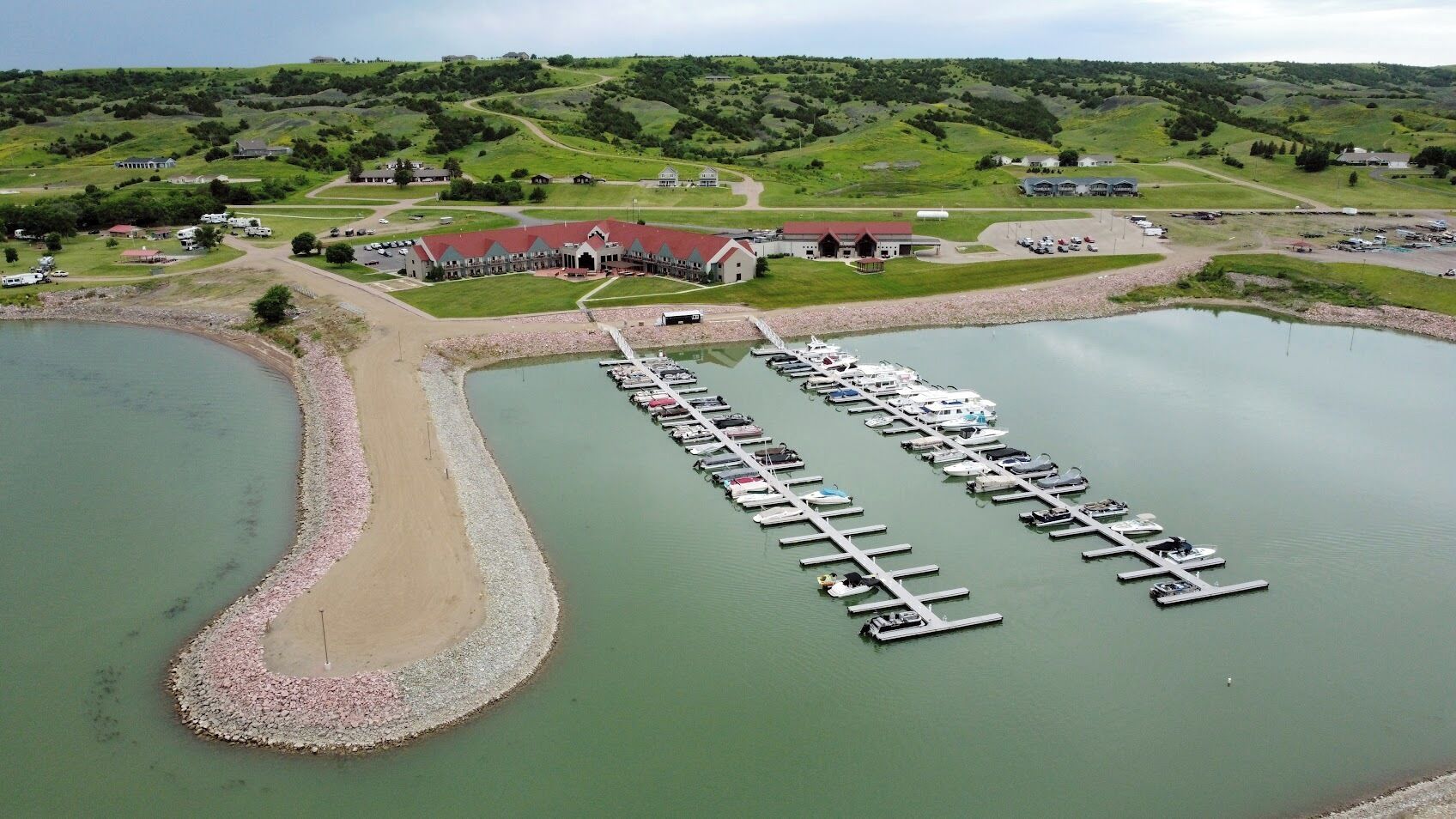 An aerial view of a marina with multiple docks and a large building in the background.