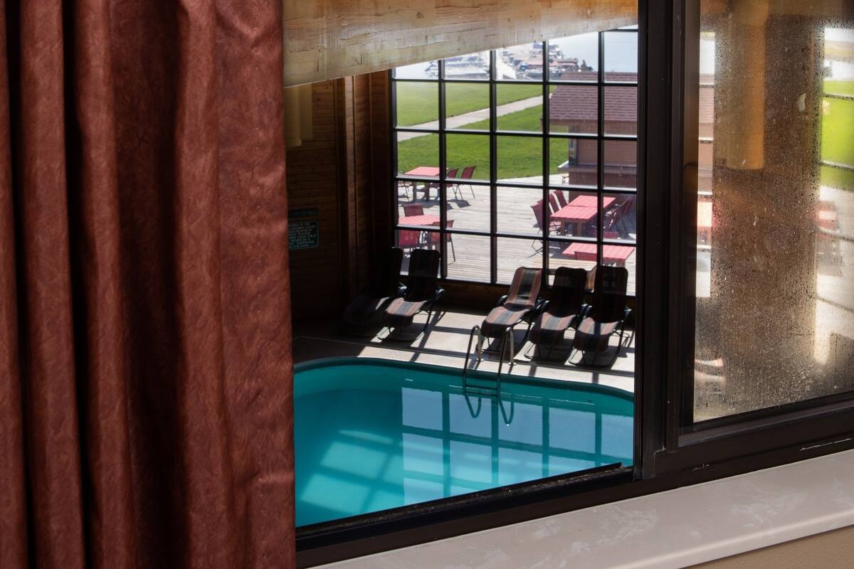 A view from a window with a pool and outdoor seating area visible.