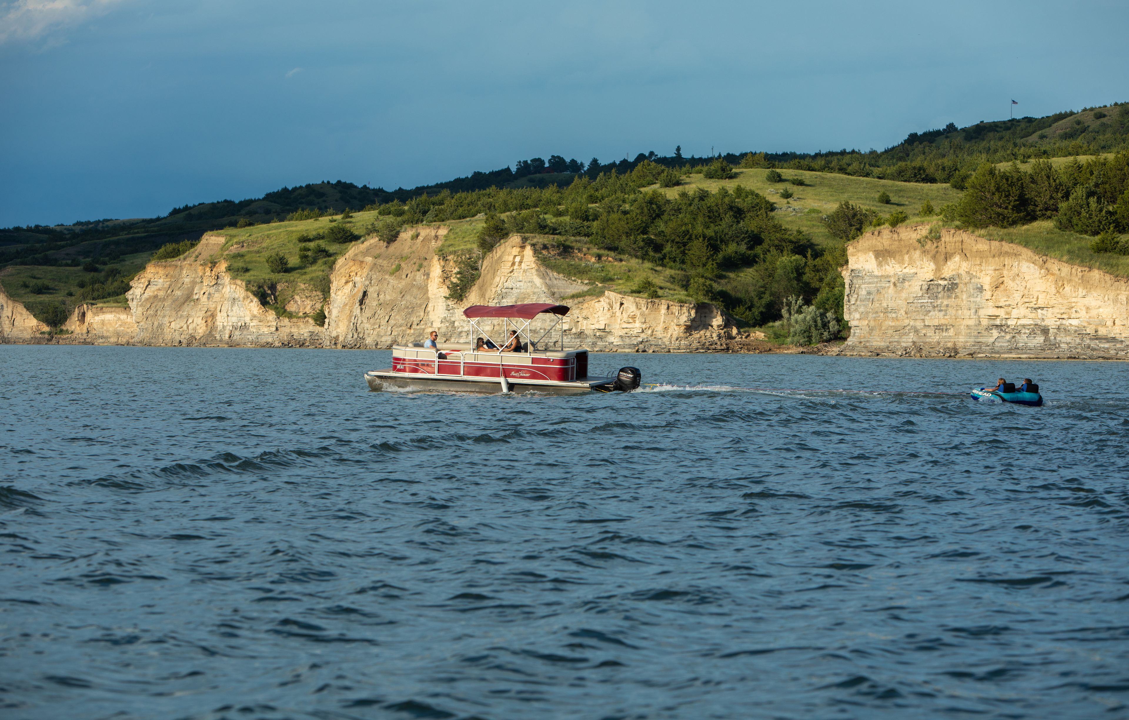A boat on a body of water with cliffs in the background.