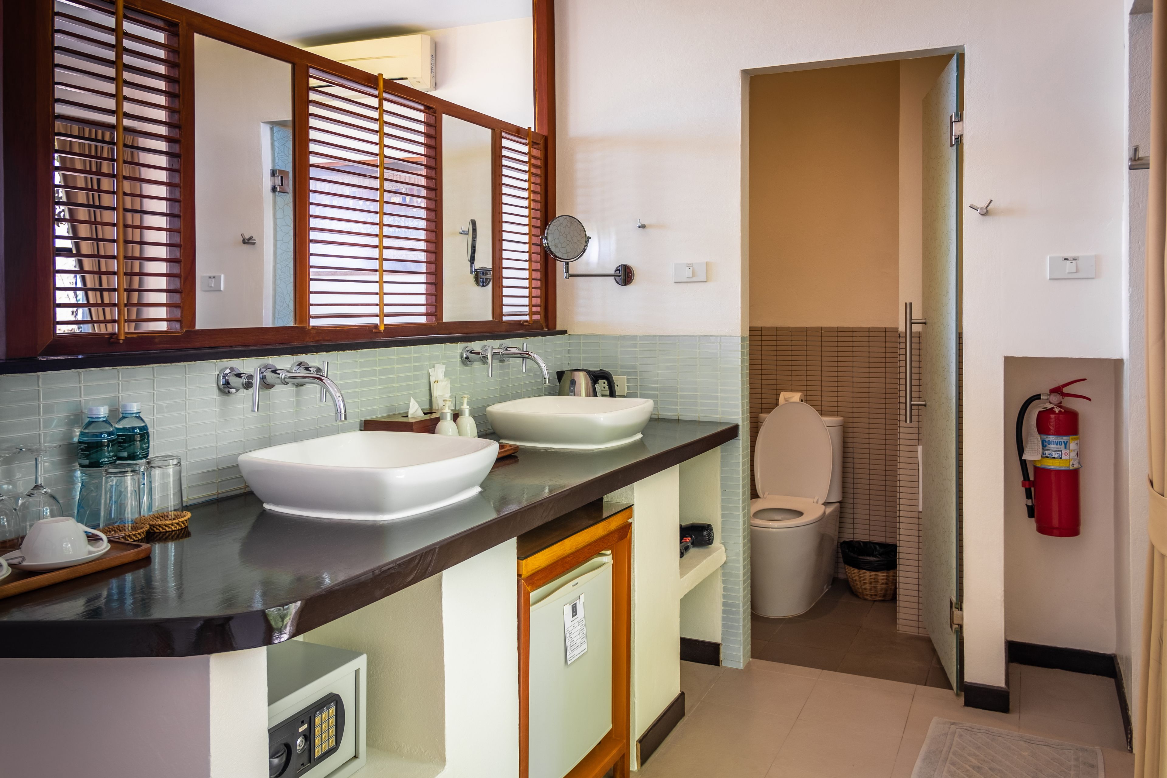 A bathroom with two sinks, a mirror, a towel rack, and a toilet.