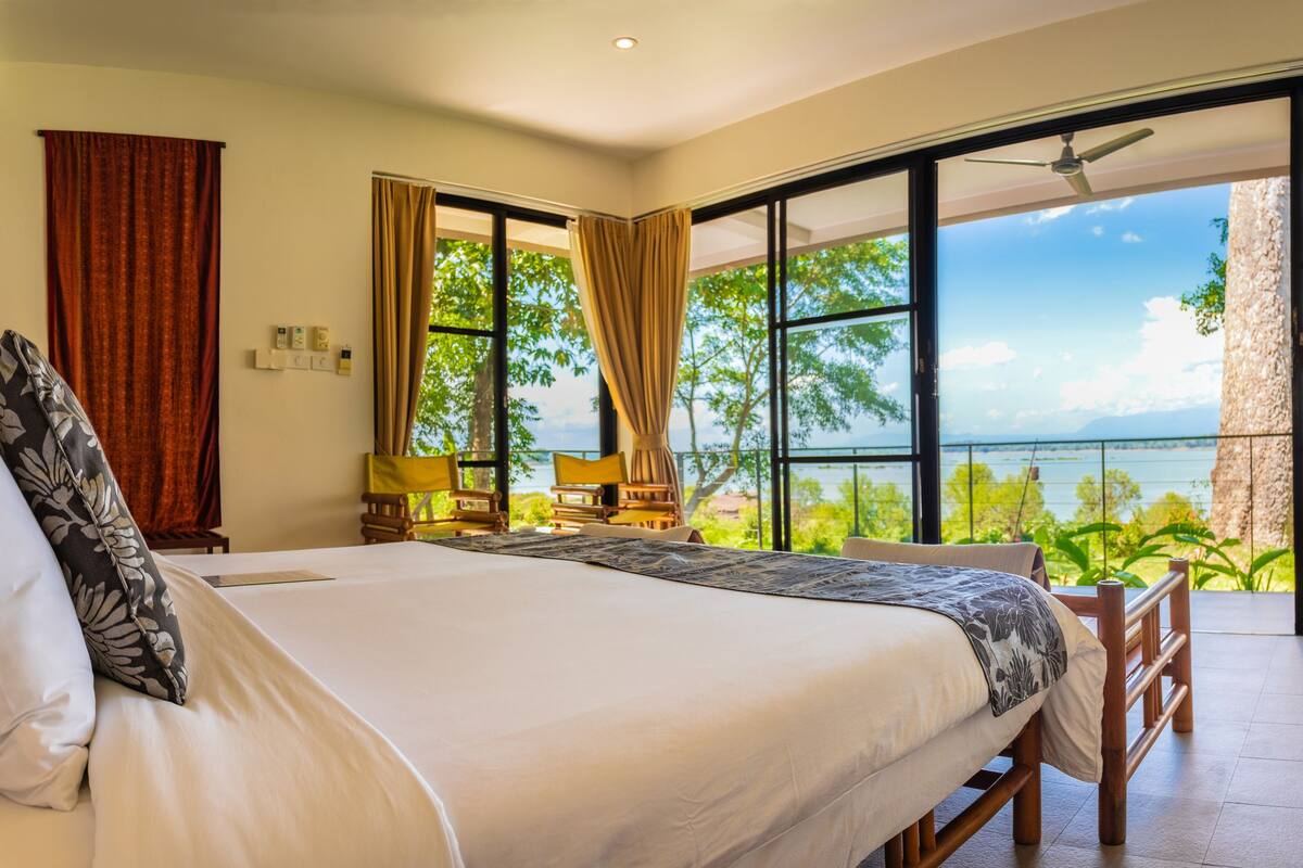 A hotel room with a large bed, a view of the outdoors, and a balcony.