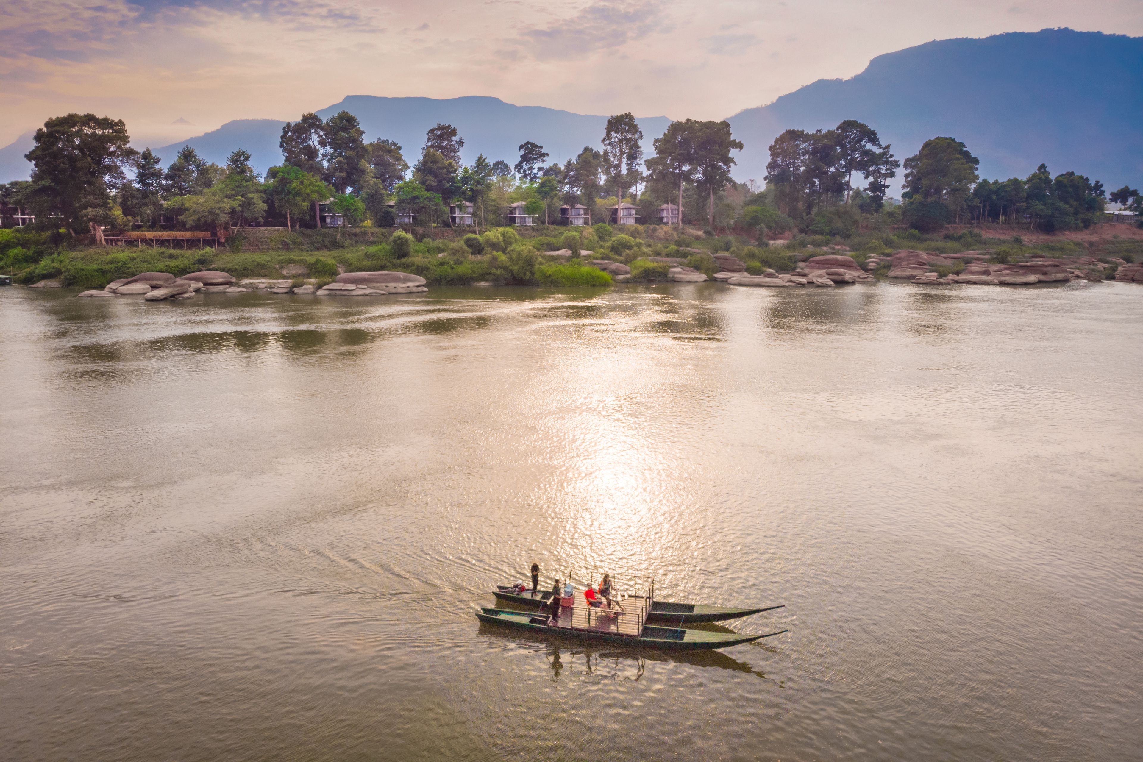 A boat on a calm river with a mountainous backdrop.