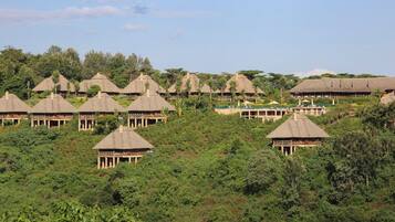 A series of thatched-roof huts arranged on a hillside, surrounded by dense greenery.