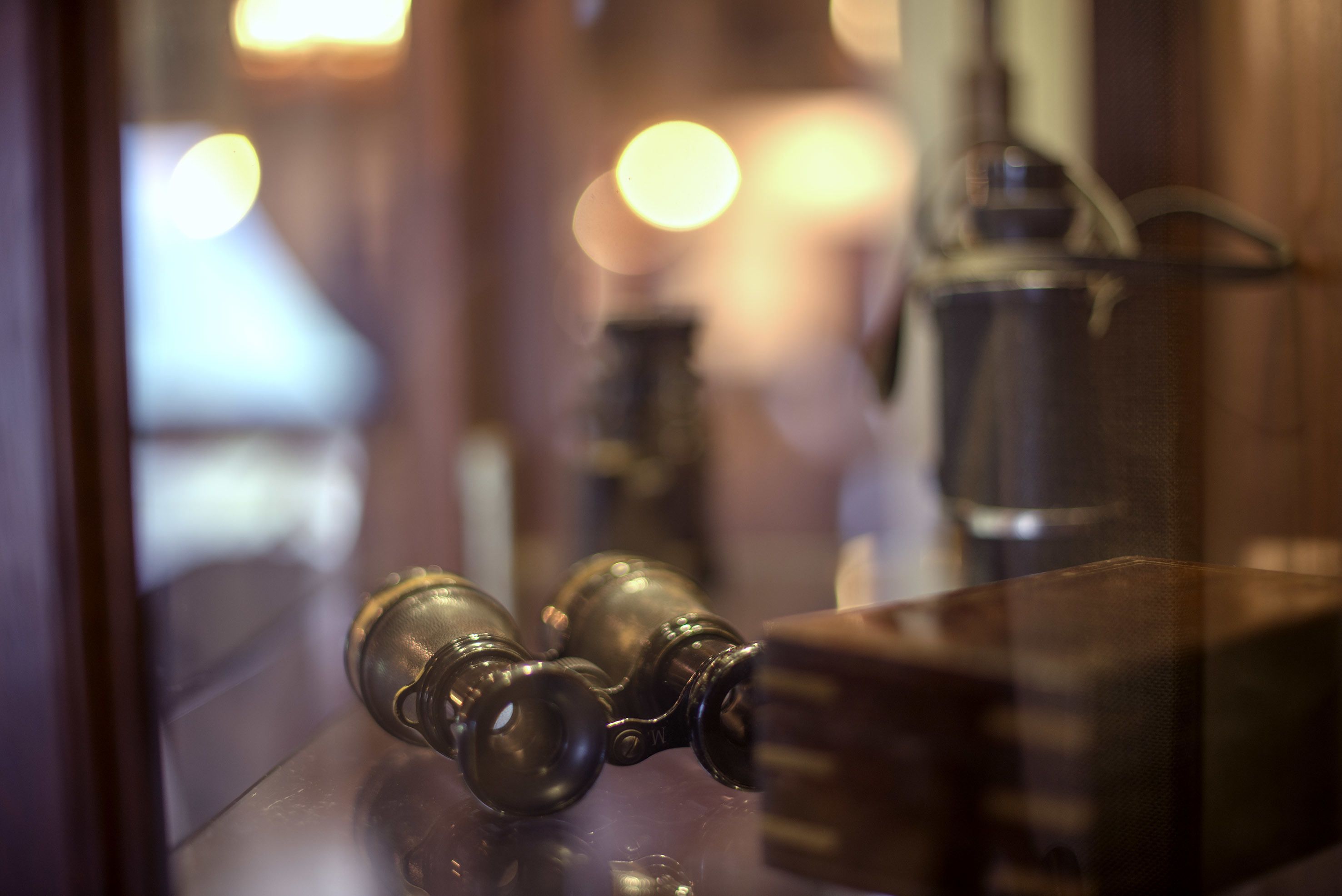 Une poignée de porte en laiton et une porte en verre qui reflète l’intérieur d’une pièce.