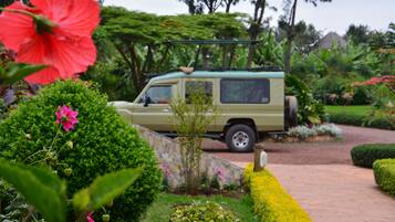 Un vehículo estacionado en un jardín con un sendero de piedra y abundante vegetación.