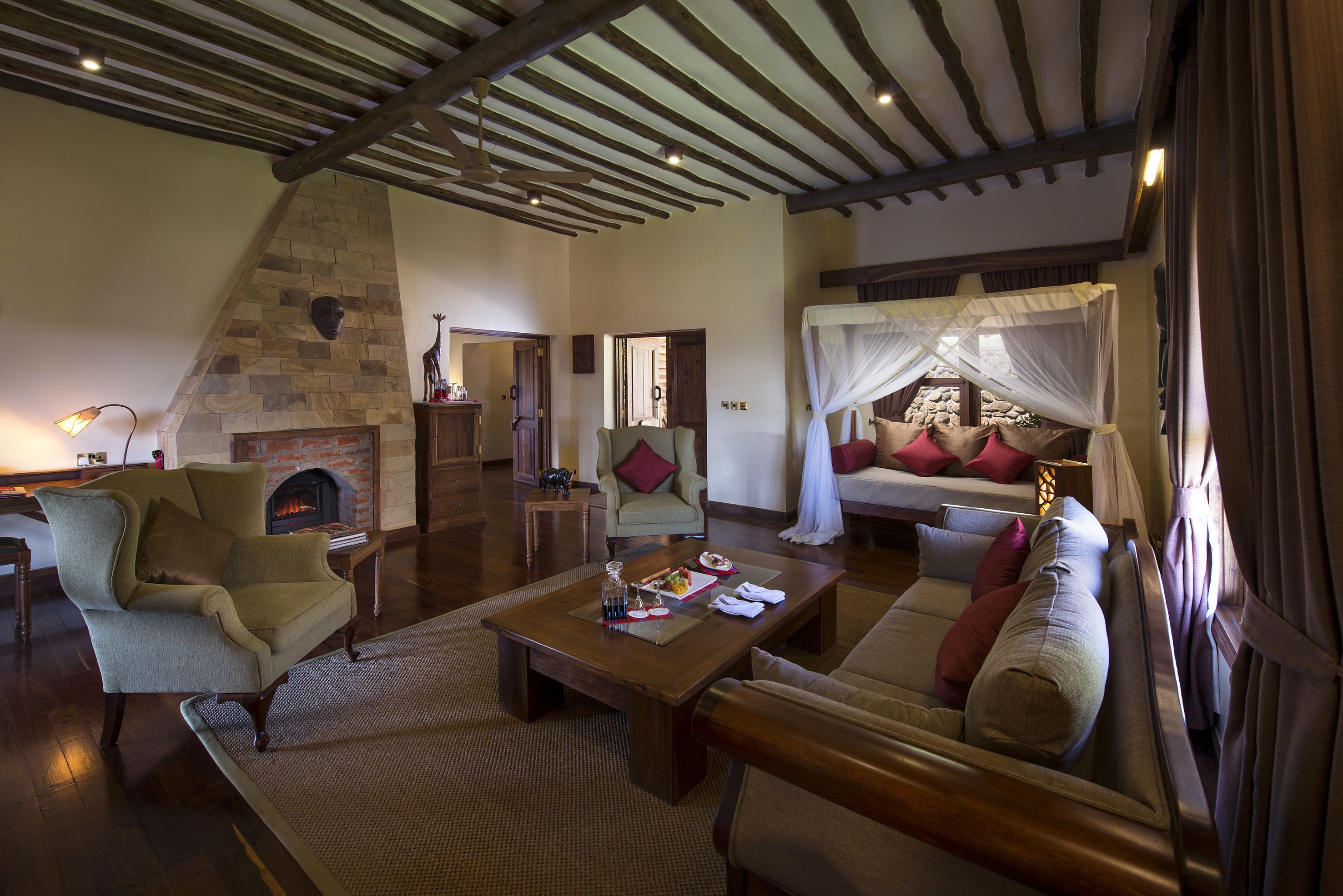 A spacious living room with a stone fireplace, a comfortable sofa, a wooden coffee table, and a high ceiling with exposed beams.