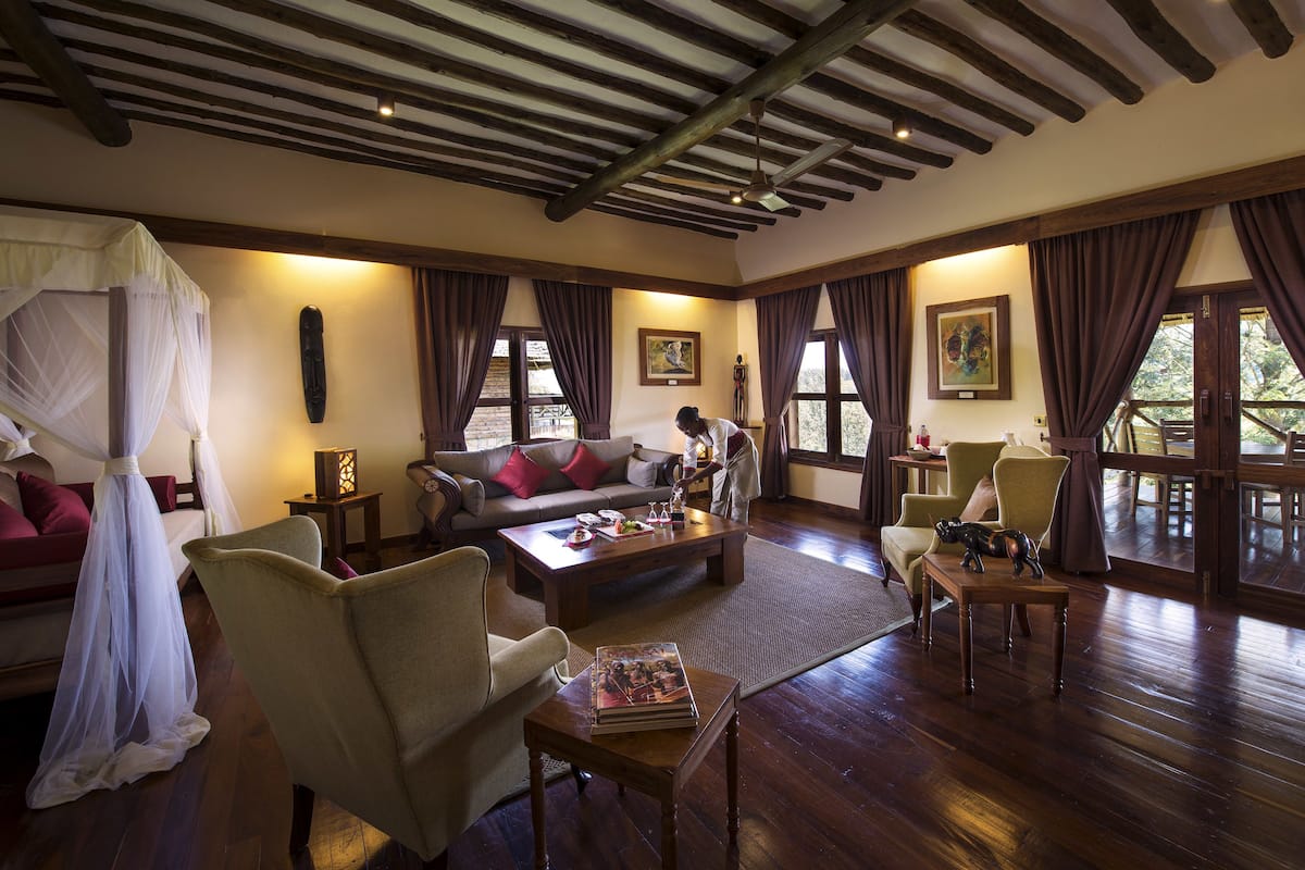 Een ruime woonkamer met houten plafond, een zithoek, een salontafel en een eethoek met stoelen.