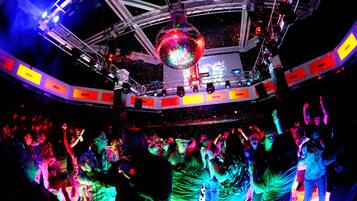 A crowded dance floor with a disco ball overhead.