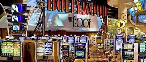 A hotel lobby with multiple gaming machines, a large illuminated sign reading "HOTEL CLUB THE ROOK," and a colorful carpet.