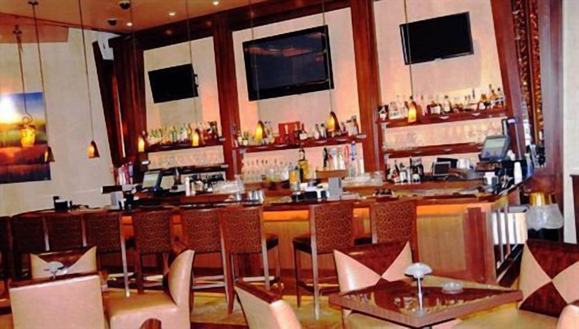 A bar area with multiple seating options, including bar stools and tables, and a counter with a computer and various items.