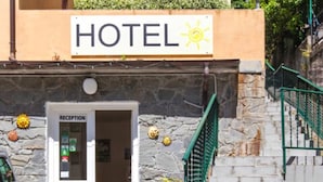A hotel entrance with a reception desk, a staircase, and a sign indicating the hotel's name. - Hotel del Sole (Riomaggiore)