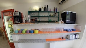 A kitchen area with a refrigerator, a coffee machine, and shelves with various items. - Hotel del Sole (Riomaggiore)