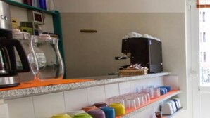 A kitchen with a countertop, colorful containers, a coffee machine, and a refrigerator. - Hotel del Sole (Riomaggiore)