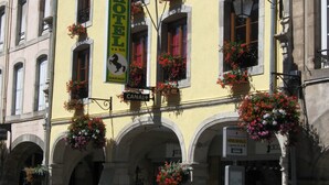 A historic building with multiple windows, some with flower boxes. A sign indicates it is a hotel.