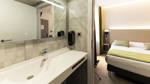 A hotel bathroom with a sink, mirror, and hand dryer.