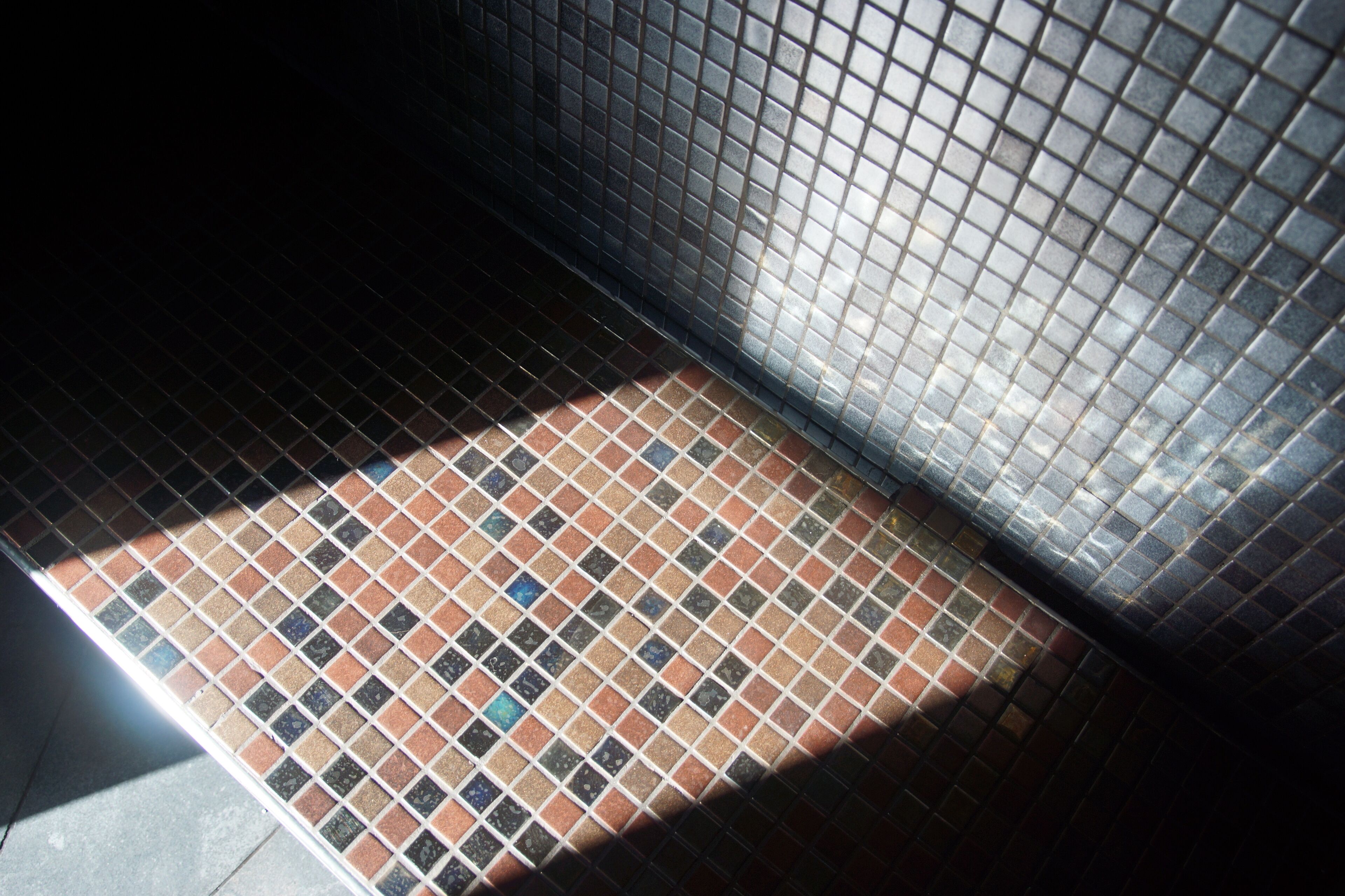 A tiled floor with a grid pattern and a metal grate.