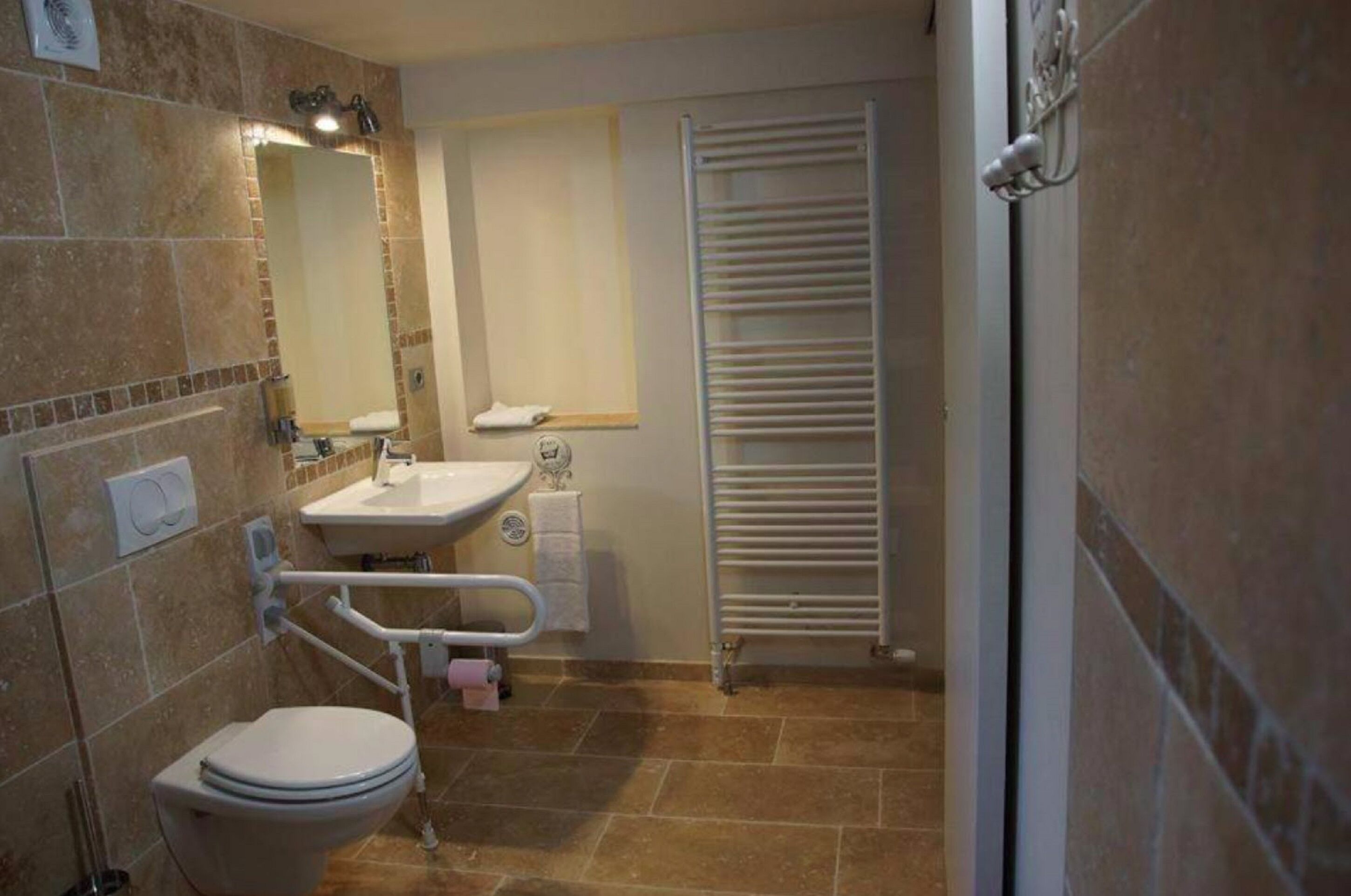 Un baño con inodoro, lavamanos, espejo, toallero y una toalla blanca en la pared.