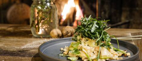 A plate of food on a wooden table with a rustic setting, including a candle and a jar of herbs in the background.