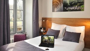 A hotel room with a bed, a laptop, a window with curtains, a nightstand, and two paintings on the wall. - Moulin des Templiers Hôtel & SPA (Pontaubert)