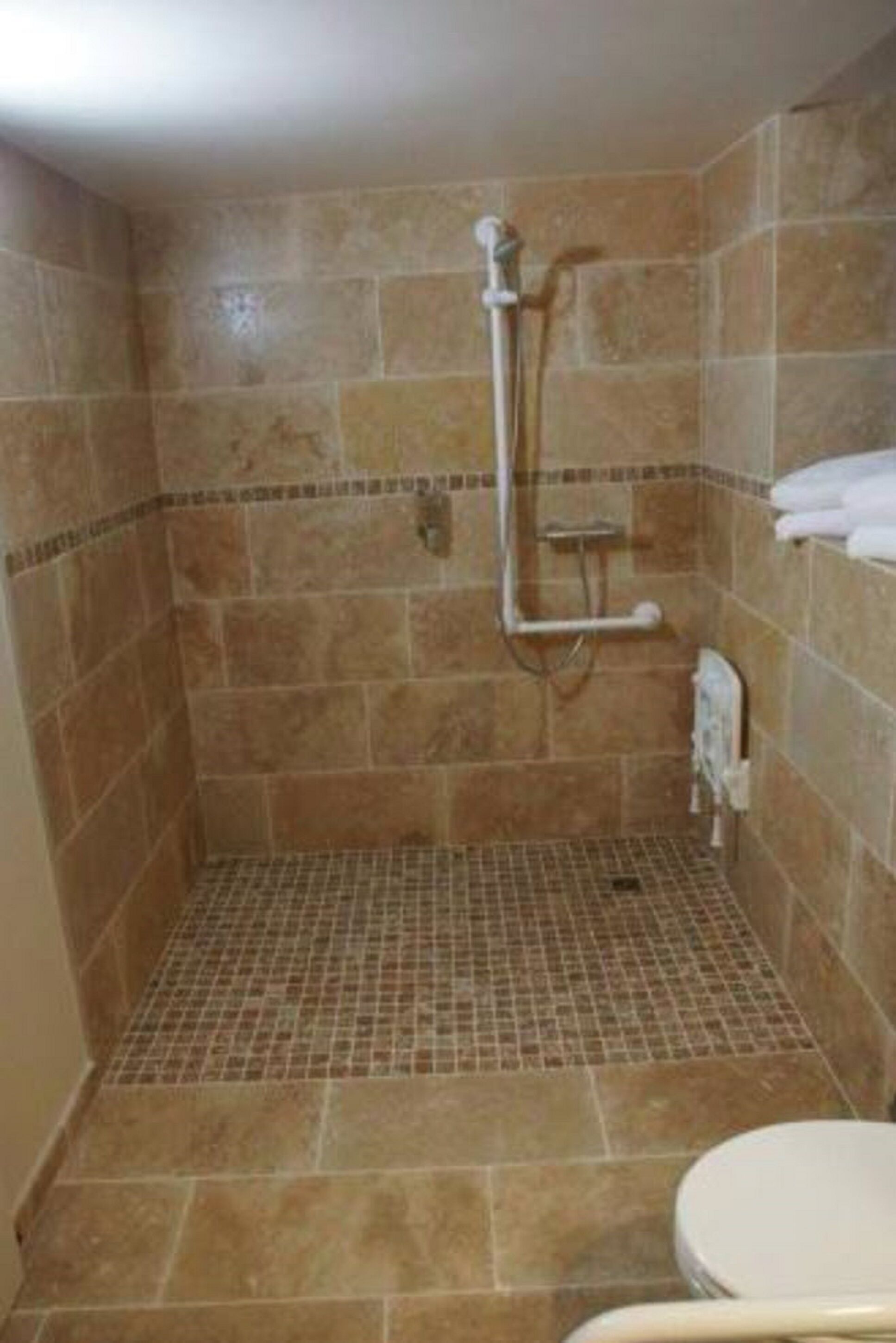 A small, tiled shower room with a showerhead and a handheld shower attachment.