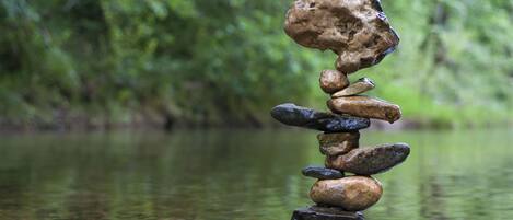 A stack of stones balanced on a rock by a calm river.