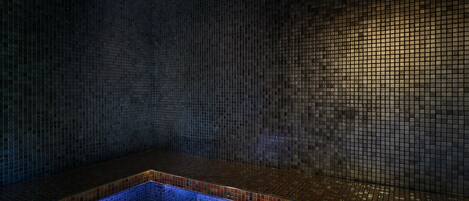 A tiled wall with a bench and a tiled floor.