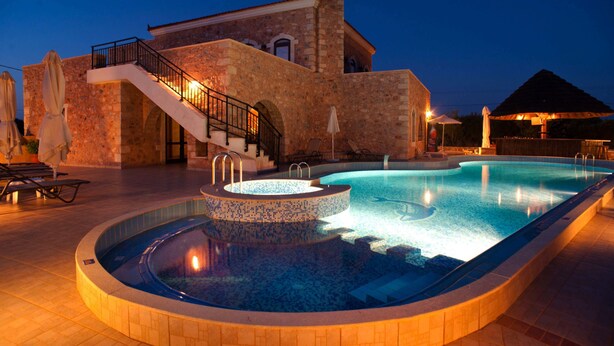 A swimming pool with a stone wall and a staircase leading to a building. - Villas and Bungalows (Apokoronas)