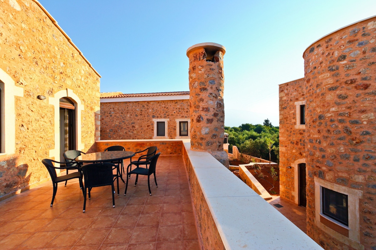 A stone building with a patio area featuring a round table and chairs.