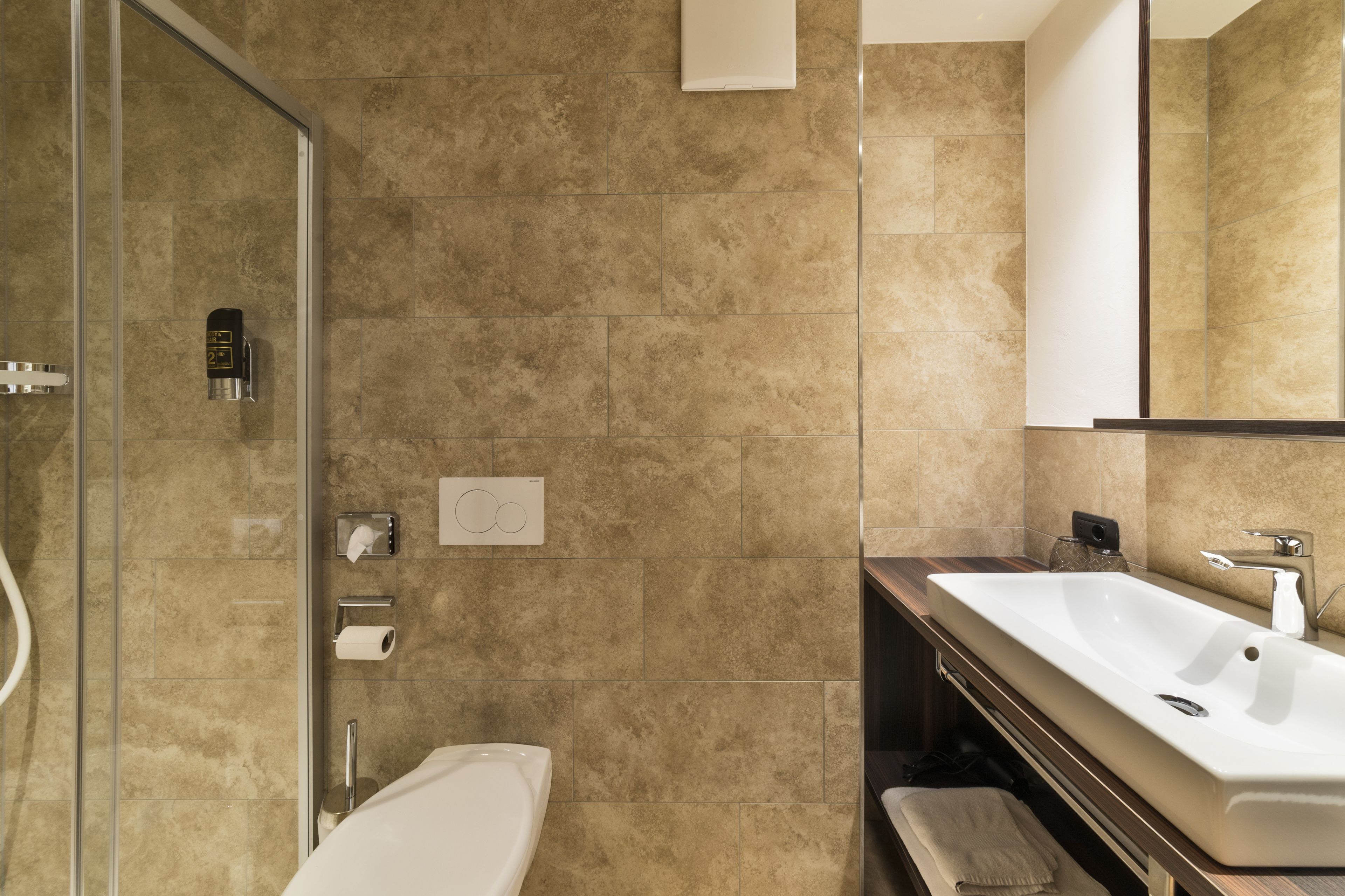 Un bagno moderno con box doccia in vetro, lavandino bianco e uno specchio grande.
