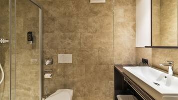 Un bagno moderno con box doccia in vetro, lavandino bianco e uno specchio grande.