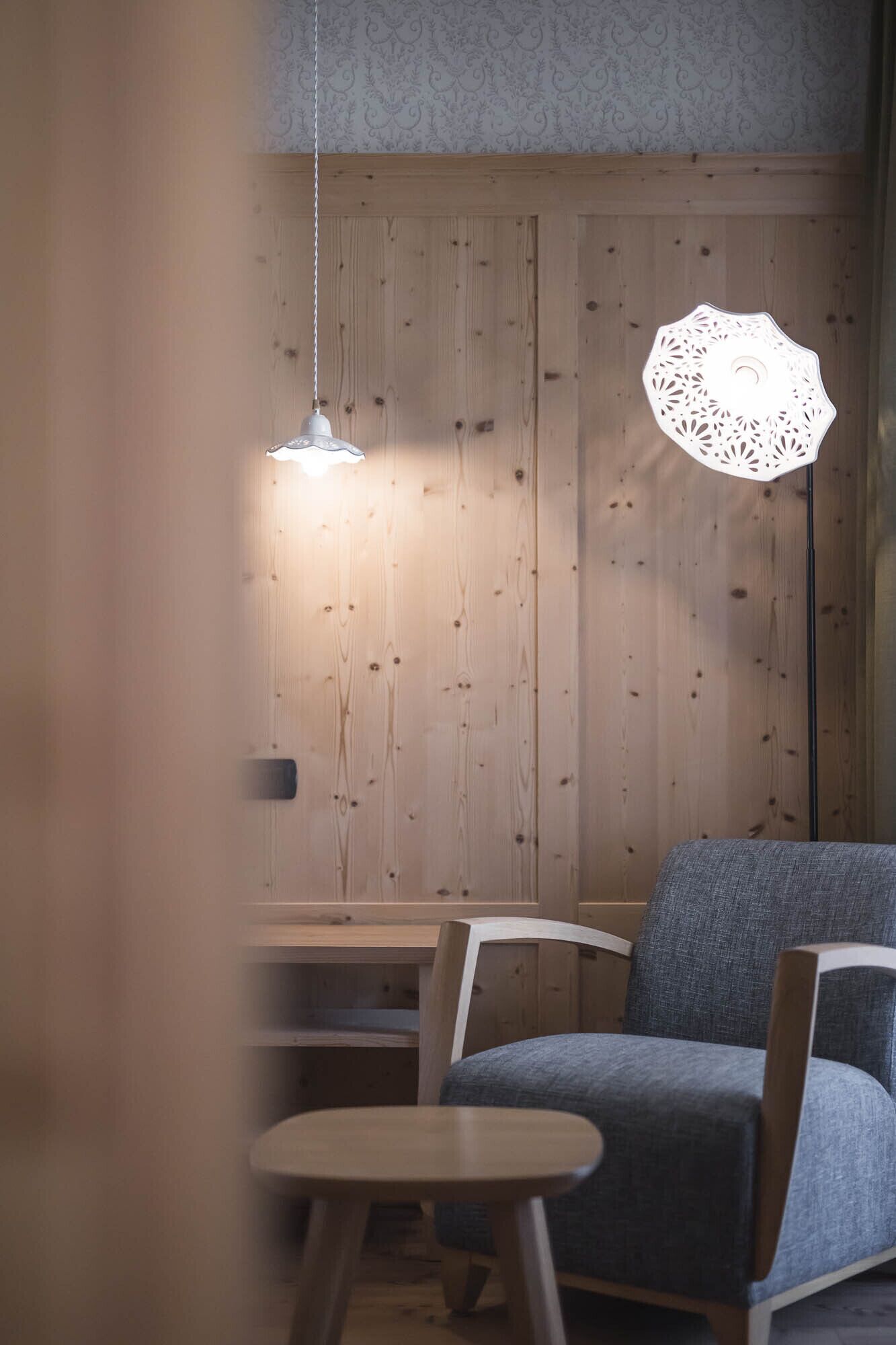 A cozy seating area with a wooden wall, a hanging light fixture, and a table.