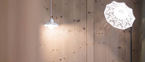 A cozy seating area with a wooden wall, a hanging light fixture, and a table.